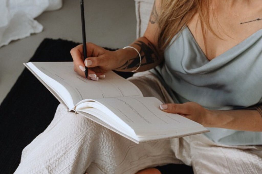 Woman making her daily entry using journaling prompts for mental health