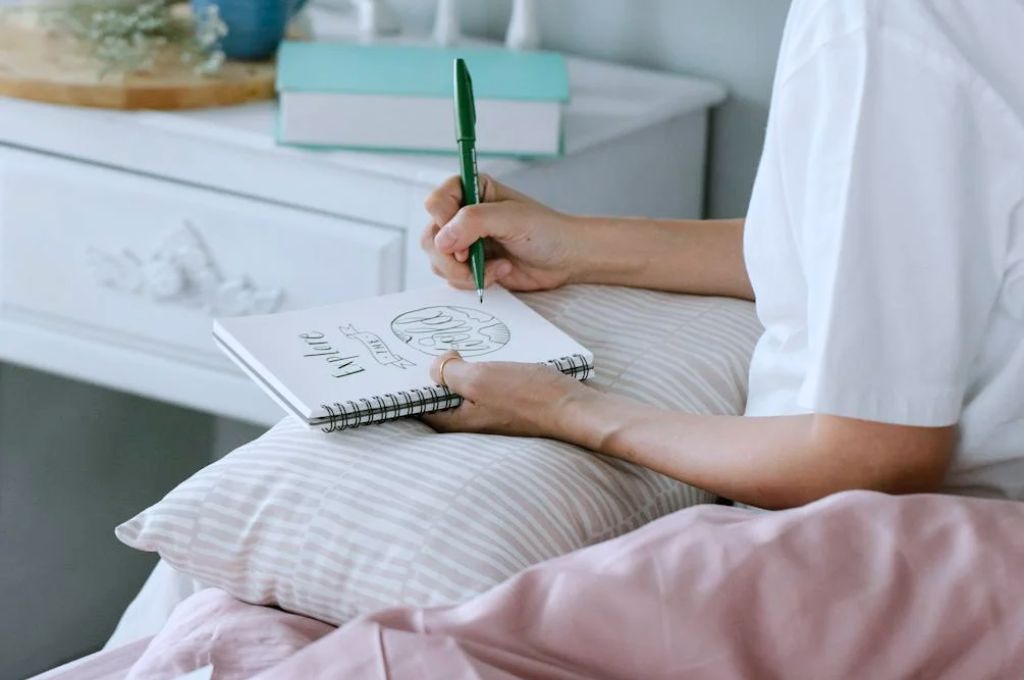 Woman writing in her journal using morning journaling prompts